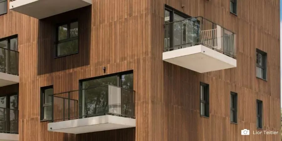 Modern apartment building with balconies, showcasing MOSO® Bamboo X-treme® wood cladding for a sleek, sustainable facade.